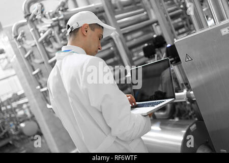 Techniker mit einem Laptop in der Hand an der Milchfabrik Stockfoto