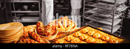 Michetta und süß Essen auf dem Tisch beim männlichen und weiblichen Baker arbeitet im Hintergrund Stockfoto