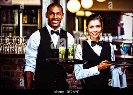 Kellner und Kellnerin hielt ein Tablett mit Glas cocktail Stockfoto