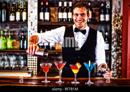 Porträt der Barkeeper Gießen einen orangenen Martini trinken im Glas Stockfoto