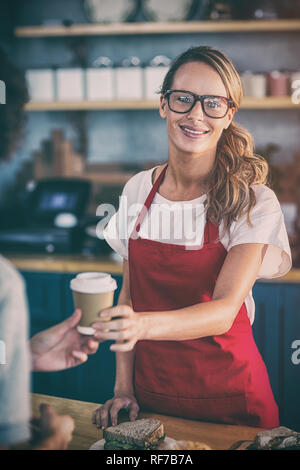 Lächelnde Kellnerin einen Kaffee an den Kunden am Schalter in cafÃƒÂ© Stockfoto