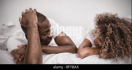 Junges Paar am Bett liegen und reden Stockfoto