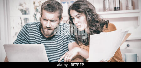 Paar, die Bezahlung ihrer Rechnungen mit Laptop in Küche Stockfoto