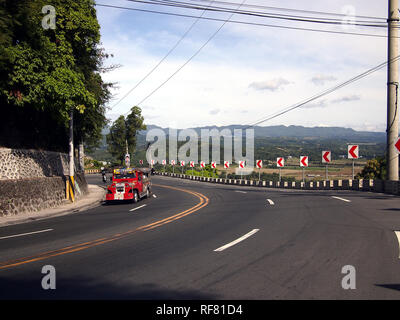 ANTIPOLO CITY, Philippinen - Januar 17, 2019: Ein Passagier jeepney führt zu einem breiten und kurvenreiche Straße in den Bergen von Antipolo City. Stockfoto