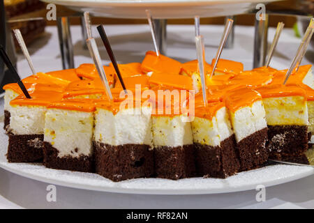 Schokolade Biskuit mit Frischkäse souffle gekrönt mit glänzend orange Glasur. Von der Seite. Close-up Stockfoto