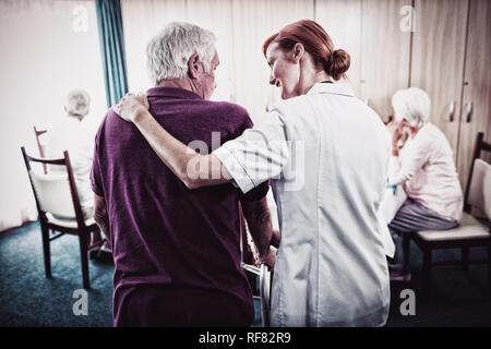 Unterstützung mit einer Gehhilfe Senior Krankenschwester Stockfoto