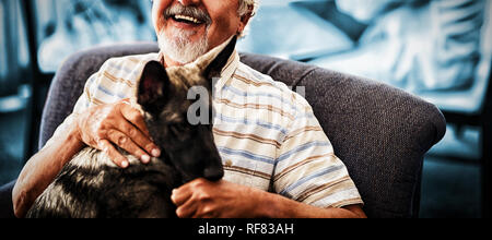 Portrait von lächelnden älteren Mann mit Hund auf Stuhl Stockfoto