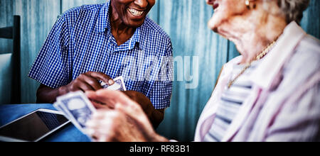 Lächelnde ältere männliche und weibliche Freunde Karten Stockfoto