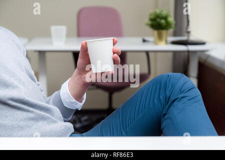 Unternehmer sitzen im Büro und in der Kaffeepause, während eine Kaffeetasse in einer Büroumgebung Stockfoto