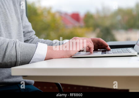 Junge Geschäftsmann Hände schreiben auf Tastatur Laptop im Büro. Männer Arbeiter und Geschäftsidee. Soft Fokus auf moderne, weiße Holztisch Stockfoto