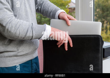 Young Business Mann ziehen einen Laptop aus einer Ledertasche im Büro Stockfoto