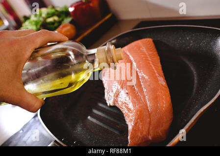 Roher Lachs filet in der Pfanne kochen gießen Olivenöl über es, um es zu kochen. Stockfoto