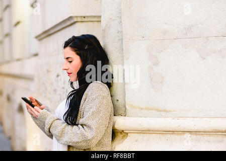 Schöne Frau Hausfrau ihr Smartphone die Kontrolle auf der Straße. Stockfoto