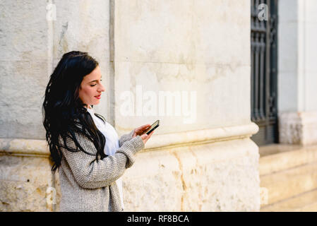 Schöne Frau Hausfrau ihr Smartphone die Kontrolle auf der Straße. Stockfoto