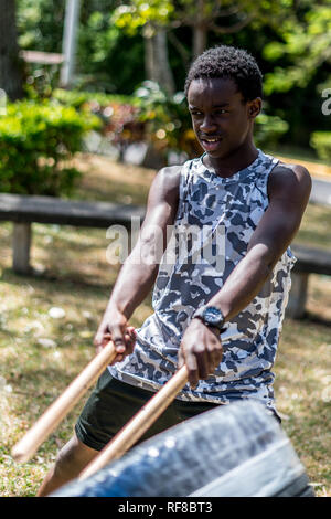 Ein afrikanischer Junge spielt eine japanische taiko Drum eines alten Reifen und Klebeband gemacht Stockfoto