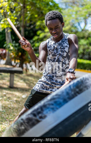 Ein afrikanischer Junge spielt eine japanische taiko Drum eines alten Reifen und Klebeband gemacht Stockfoto