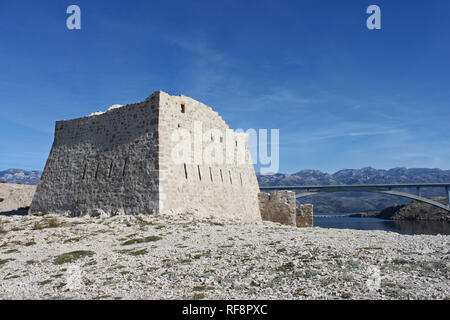 Ruinen der alten Festung Fortica auf der Insel Pag (Kroatien). Die Brücke verbindet die Insel mit dem Land im Hintergrund. Stockfoto