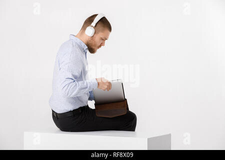 Unternehmer im Kopfhörer setzt Laptop in der Abdeckung Stockfoto