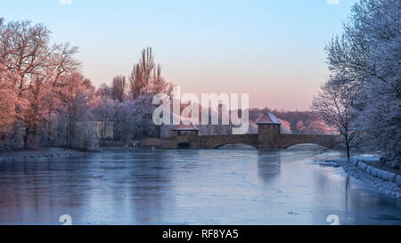 Leipzig im Frost, vereister Fluss Weiße Elster und Palmengartenwehr im roten Licht der aufgehenden Sonne Stockfoto
