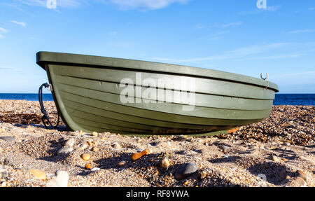 Low Angle Nahaufnahme von einem grünen Glasfaser oder Plastik Ruderboot am Strand von Ringstead Bay, Dorset, Großbritannien Stockfoto