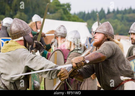 Mittelalterliche Re-enactors in Rüstung und Kostüme des 12. Jahrhunderts mit Schwertern und Schilden ausgestattet gekleidet nachgespielt Bekämpfung des Zeitraums Stockfoto