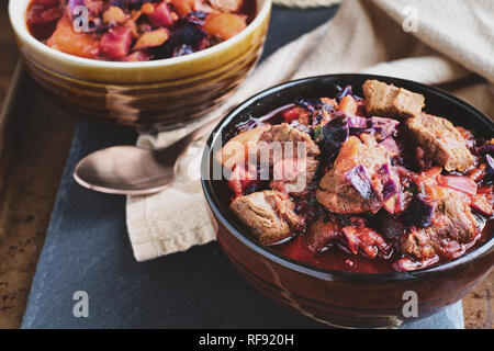 Schüssel von Borscht Suppe mit herzhaften, fleischigen Brocken von Rindfleisch, Wurzelgemüse, Kraut und Rüben. Hohe Blickwinkel betrachten. Stockfoto