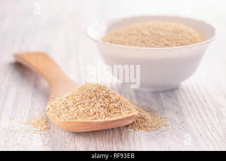 Trockene Haferkleie in eine weiße Platte auf hellem Holztisch mit einem Holzlöffel. Das Konzept der gesunden Ernährung und Gewicht zu verlieren Stockfoto