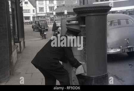 1950, historische, GPO Briefträger tragen Cap beim Entleeren eines High Street Post Box, England, UK. Stockfoto