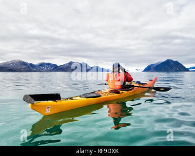 SVALBARD, Norwegen - Kajaktouristen erkunden das eisige Wasser und die unberührten Landschaften der Arktis rund um Svalbard. Diese einzigartige und abenteuerliche Form des Tourismus bietet ein Erlebnis aus nächster Nähe mit der arktischen Umgebung und zeigt die atemberaubende Schönheit und empfindliche Ökosysteme der Region. Stockfoto