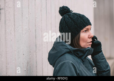 Ernsthafte Frau Gespräch am Handy draußen in der Kälte des Winters Tag Stockfoto
