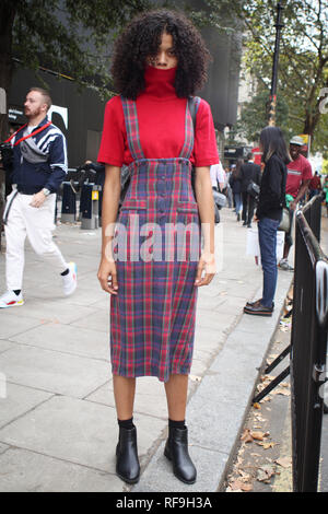 LONDON, Großbritannien - 14 September 2018: Leute auf der Straße, während der London Fashion Week. Curly girl in einem roten Rollkragenpullover und eine hohe Bleistiftrock Stockfoto