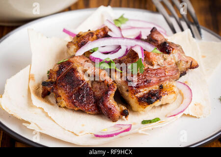 Kebab, Stücke Fleisch, Rind, Schwein auf dünnes Fladenbrot mit Zwiebeln und Salat Stockfoto