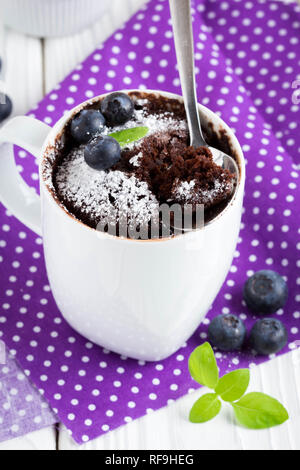 Schokoladenkuchen in einem Becher mit Heidelbeeren und Puderzucker, köstliche Sommer Dessert Stockfoto