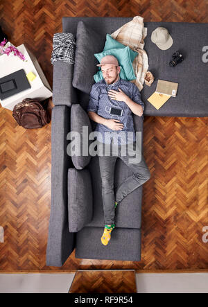 Ein junger Mann, der Coolness im Bett schlafen. Ganze Sofa und Bett sichtbar, Ansicht von oben. Stockfoto