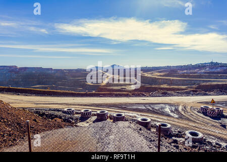 Der Tagebau Steinbruch von Riotinto mit Maschinen arbeiten. Dieser Bereich hat für Kupfer und Gold gefördert worden, den blauen Himmel mit Wolken Hintergrund Stockfoto