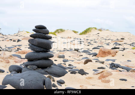 Cairn aus schwarzen vulkanischen Kieselsteinen am Strand an der südlichen Küste der Insel Boa Vista, Kap Verde Inseln, Afrika. Stockfoto