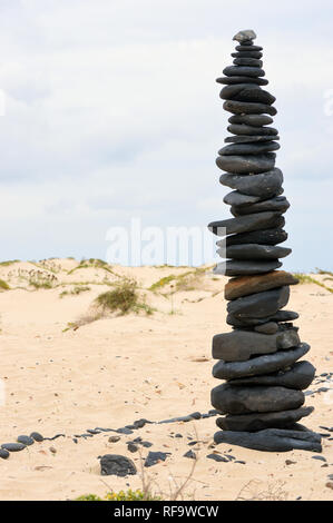 Cairn aus schwarzen vulkanischen Kieselsteinen am Strand an der südlichen Küste der Insel Boa Vista, Kap Verde Inseln, Afrika. Stockfoto