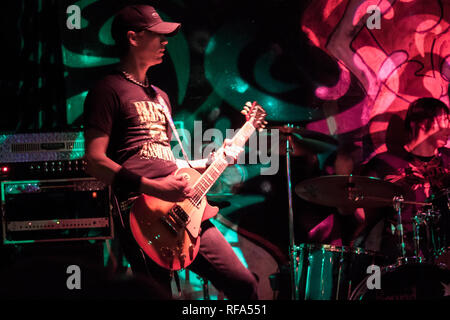 Gitarrist in einer Band spielen auf der Bühne mit bunten psychedelischen wie Lichter scheint auf Sie. Stockfoto