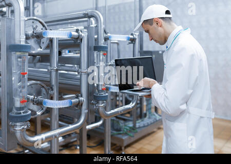 Techniker mit einem Laptop in der Hand an der Milchfabrik Stockfoto