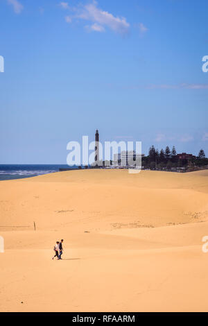 Menschen zu Fuß auf die Dünen von Maspalomas gegen Leuchtturm von Maspalomas im Sommer Stockfoto