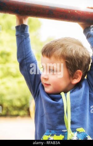 Cute little boy hängen an horizontalen Balken im Freien Stockfoto