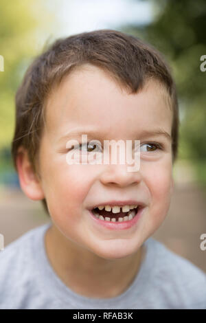 Im freien Nahaufnahme Portrait von Lachen sommersprossigen Jungen mit dunklen Haaren und braunen Augen Stockfoto