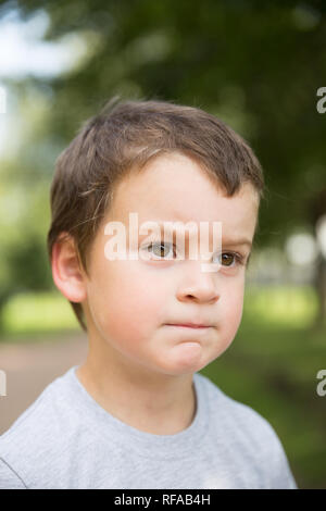 Closeup Portrait von traurigen sommersprossigen Jungen mit dunklen Haaren und braunen Augen im Freien Stockfoto