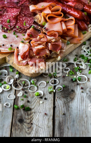 Mischung aus Fleisch Vorspeisen - Salami, Schinken, geräucherte Türkei, Wurst und Schinken - auf rustikalen hölzernen Hintergrund Stockfoto