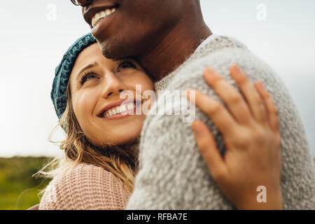 Lächelnde Frau ihrem Freund umarmen und sah ihn an. Frau, die ihren Mann mit Liebe. Stockfoto
