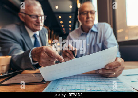 Geschäftsleute treffen sich im Restaurant und arbeiten über das Budget des neuen Projekts. Leitende Geschäftsleute diskutieren über Bericht im Café. Schwerpunkt auf Finanz-Repo Stockfoto