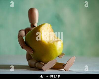 Eine hölzerne Figur mit einem gebissen Green Apple auf einem Tisch Stockfoto