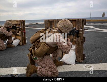 Mittelmeer (Jan. 21, 2019) Marines mit dem Bataillon Landung Team, 1.BATAILLON, 2. Marine Regiment, 22 Marine Expeditionary Unit, Feuer aus hinter Abdeckung beim Üben sofortige Aktion Bohrer auf dem Flug-Deck der USS Arlington LPD (24) in das Mittelmeer, Jan. 21, 2019. Die USS Arlington einen geplanten Einsatz als Teil der 22 MEU und der kearsarge Amphibischen bereit, zur Unterstützung der Maritime Security Operations, Krisenbewältigung und Theater Zusammenarbeit im Bereich Sicherheit und zugleich eine vorwärts Naval und Marine Präsenz. (U.S. Marine Corps Foto von Personal Stockfoto