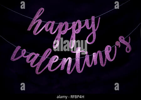 Happy Valentine's Nachricht in funkelnden handschriftliche Rosa script Banner einen dunklen schwarzen Hintergrund hängenden Stockfoto