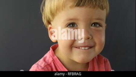 Junge schaut in die Kamera lächeln und Stockfoto